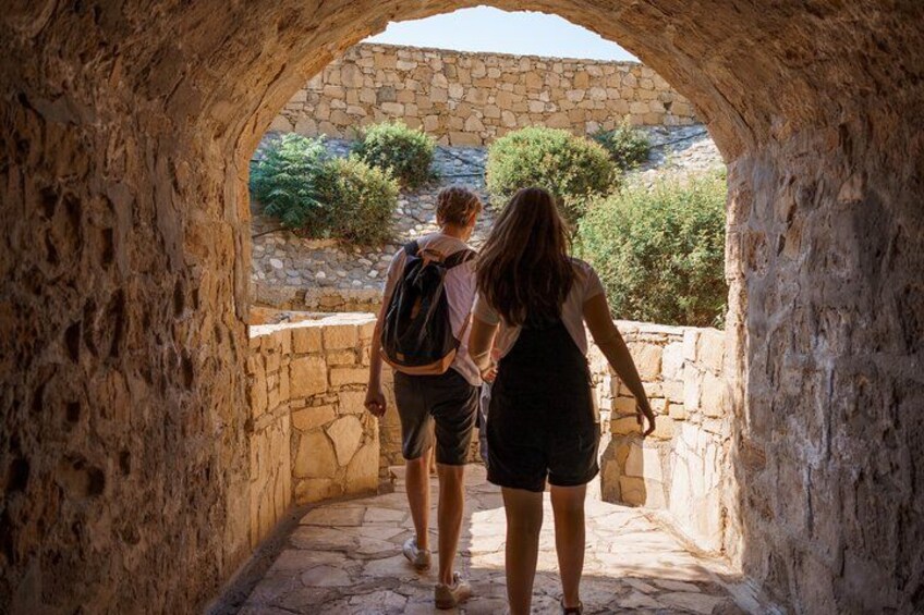 Two people walking through a stone archway. 5