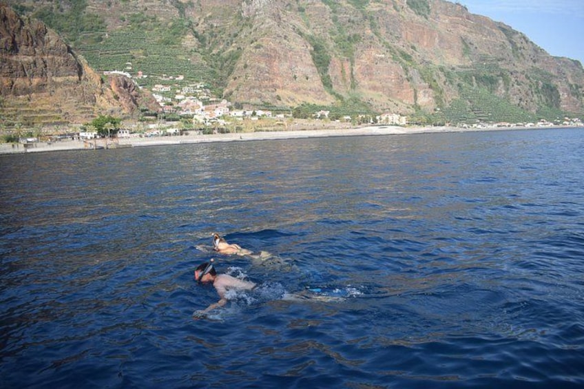 A person swimming in a body of water with a mountainous landscape in the background. 2
