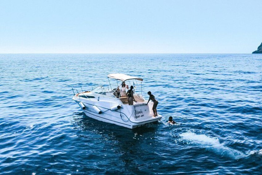Ein weißes Boot mit Personen an Bord und eine Person, die im Wasser schwimmt. 2