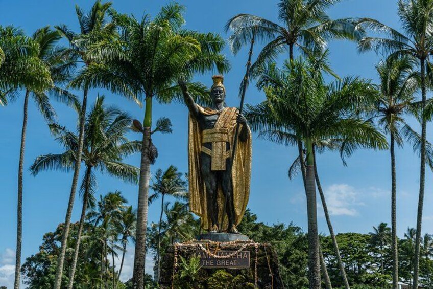 A statue of a figure with a golden robe, surrounded by palm trees. 3