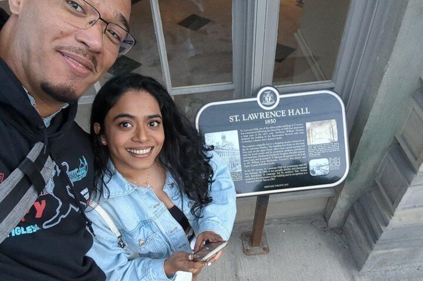 Two people standing in front of a historical marker for St. Lawrence Hall. 5