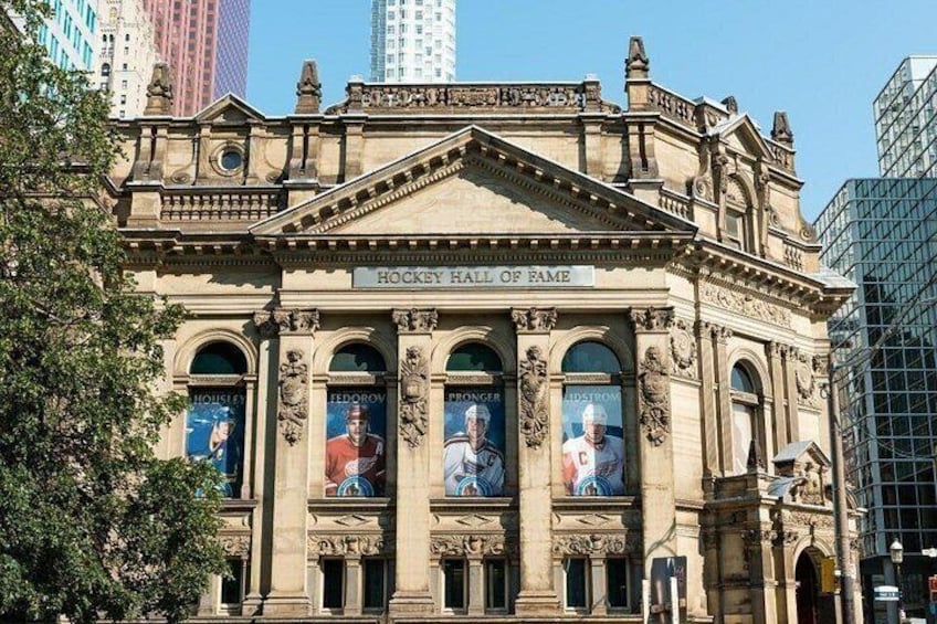 A historic building with ornate architecture, a prominent entrance, and a sign reading 'Hockey Hall of Fame'. 3