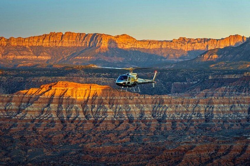 Un hélicoptère survole un canyon aux formations rocheuses en strates. 1