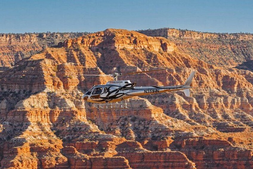 Un hélicoptère survole un paysage accidenté, composé d’un canyon rocheux. 2