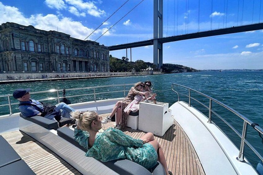 Un bateau sur lequel des personnes se détendent sur le pont, un grand pont en arrière-plan et une étendue d’eau. 2