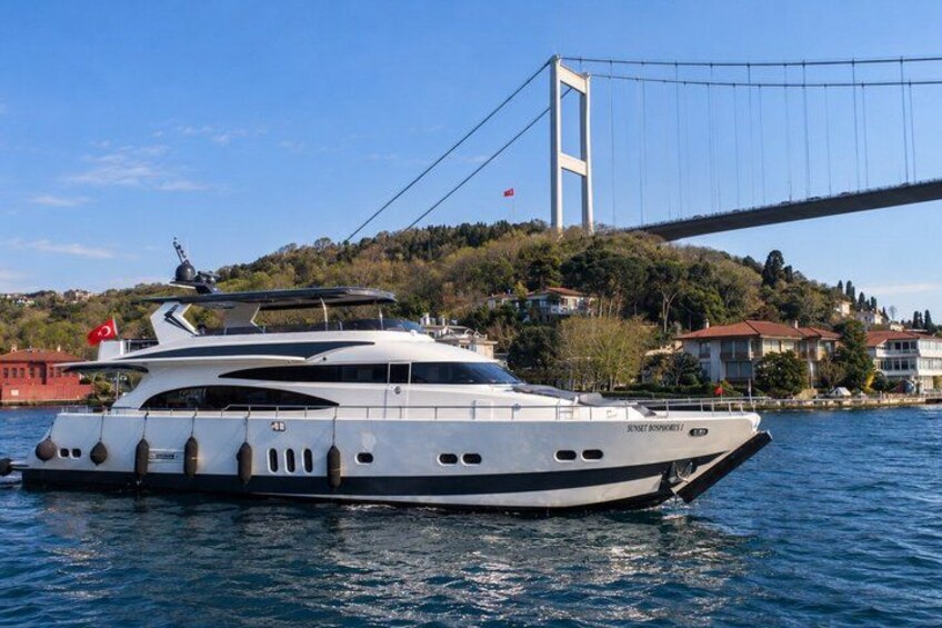 Un grand yacht était amarré près d’un pont, avec une chaîne de montagnes en arrière-plan. 1