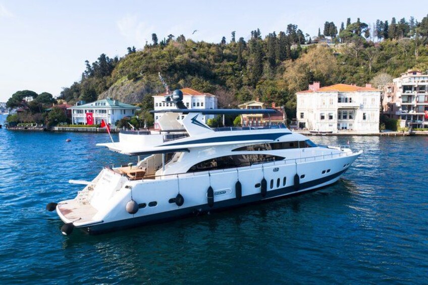 Un yacht blanc est amarré dans une marina, avec des bâtiments et des arbres en arrière-plan. 3