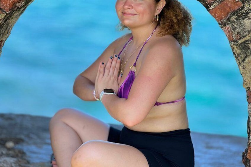 Una persona sentada en la playa con un cielo azul despejado y el océano al fondo. 4