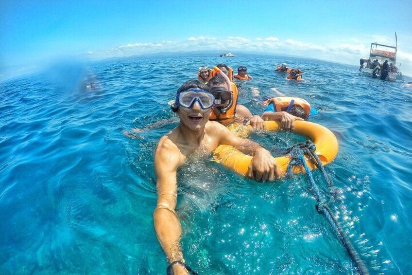 People snorkeling in clear blue water with a boat in the background. 1