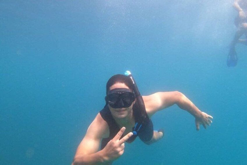 A person underwater, wearing a snorkel and fins, with a clear blue water background. 3