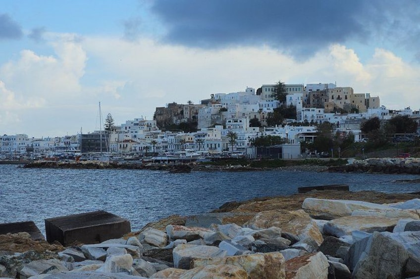 A coastal town with white buildings, rocky shoreline, and a cloudy sky. 3
