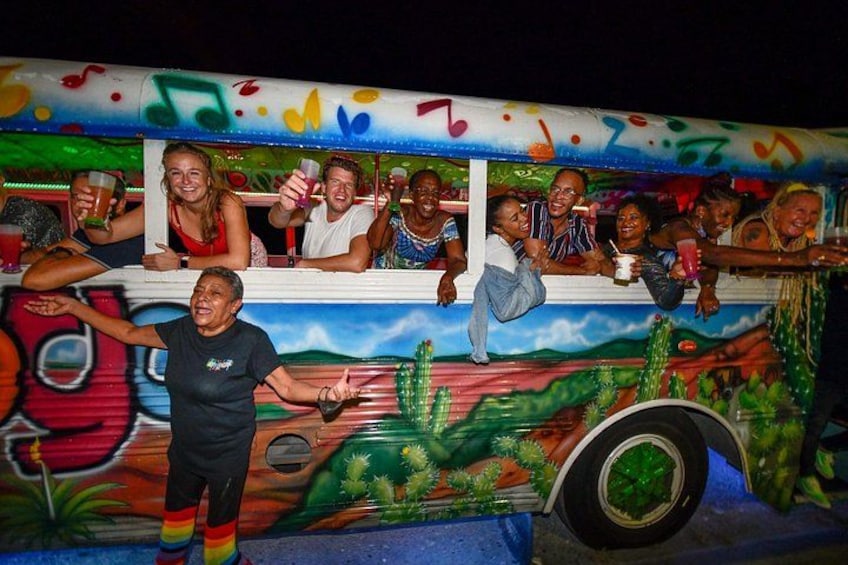 A colorful bus with a mural, passengers holding drinks, and a person in a black shirt and striped socks. 2