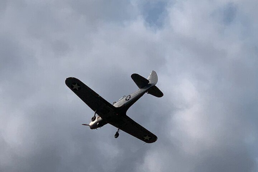 Een oud militair vliegtuig vliegt tegen een bewolkte lucht. 5