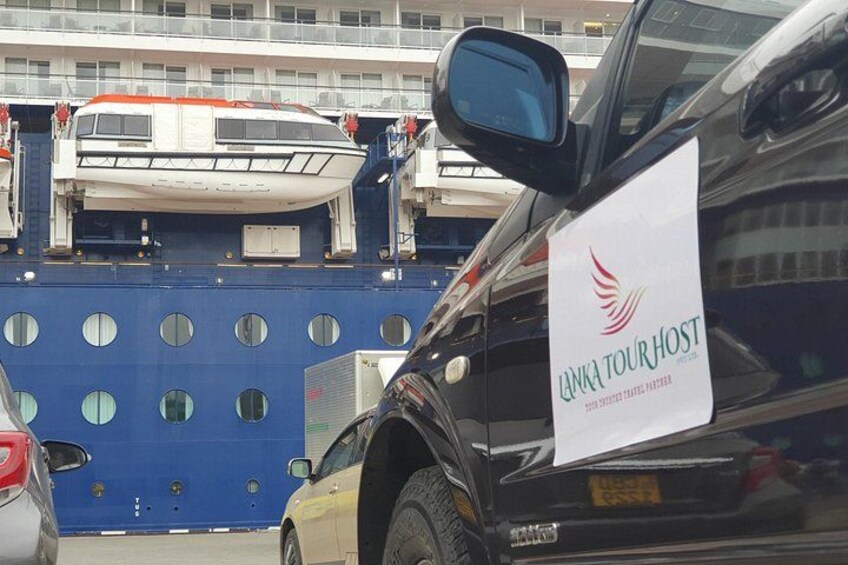 A car with a sign that reads 'Lanka Tour Host' and a blue structure with circular windows. 4