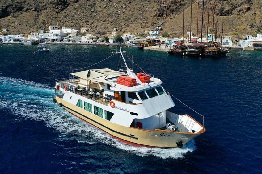 A boat named 'Calypso' moving through a body of water with a coastal town in the background. 1
