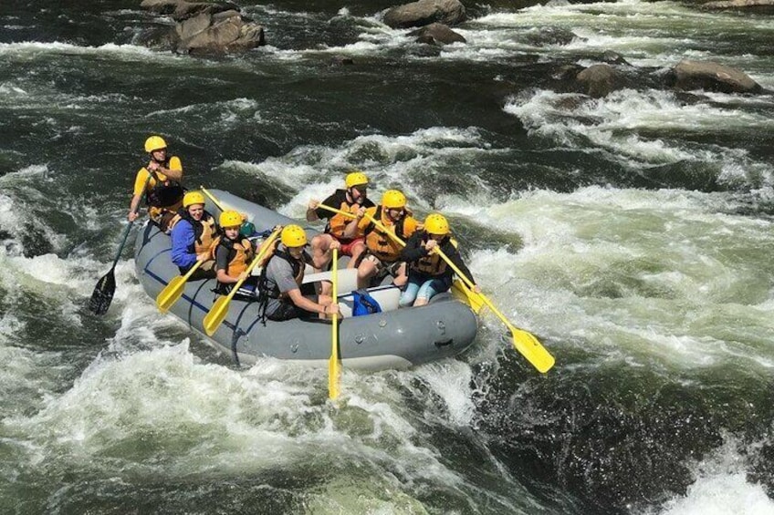 Een groep mensen in een raft die een rivier met stromingen bevaart. 4