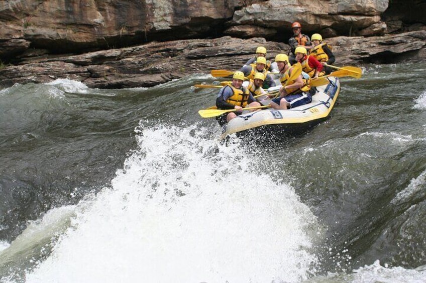 Een groep mensen peddelt in een raft over een rivier. 2