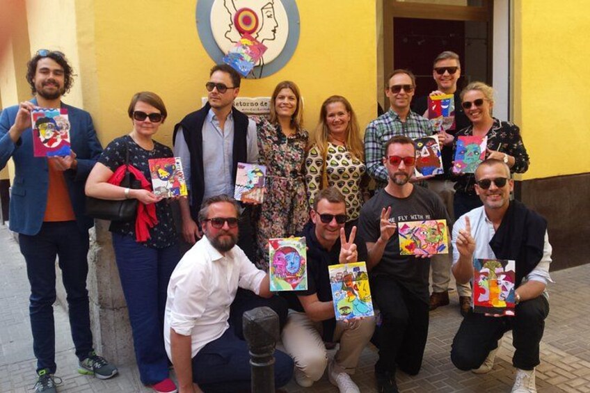 Un gruppo di persone che tiene libri colorati di fronte a un edificio giallo con un logo circolare. 3