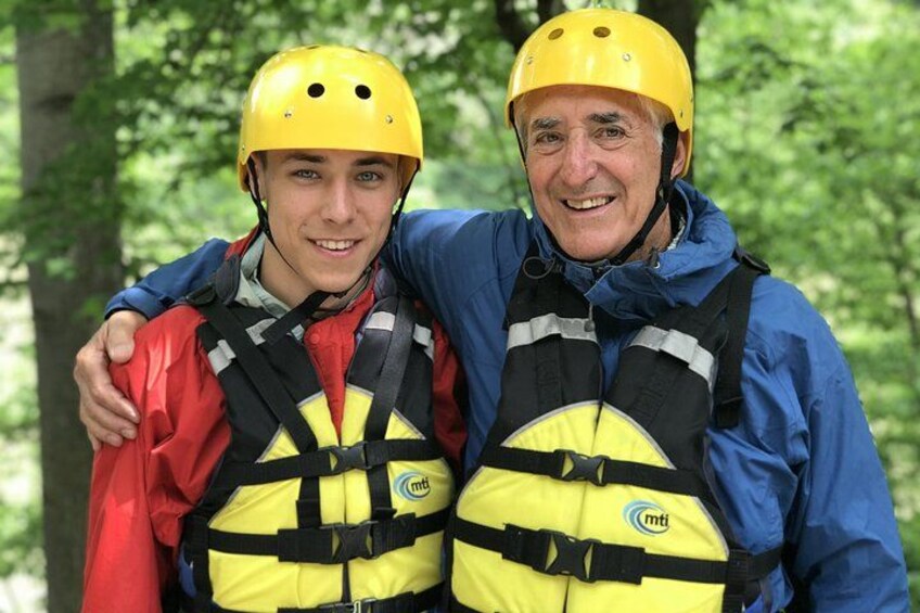 Two people wearing helmets and life jackets, standing in a forest. 2