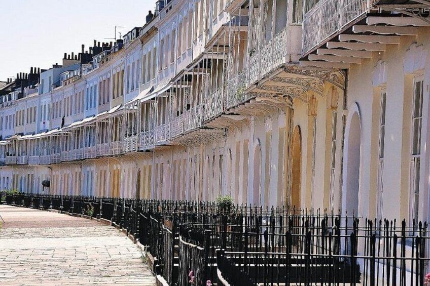 A row of old, weathered buildings with balconies and a black metal fence. 5