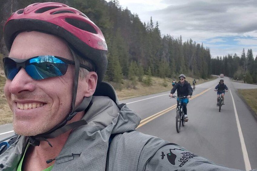 A person on a bicycle on a road with forest on both sides. 4