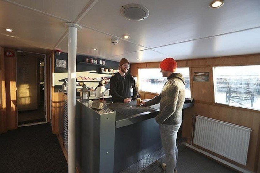 A person standing at a counter inside a train, with another person behind the counter. 4