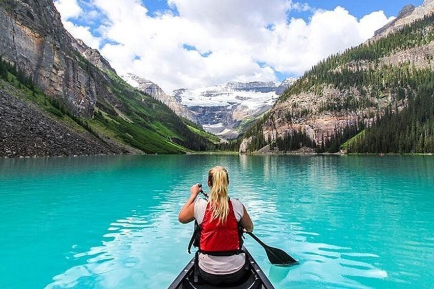 A person kayaking on a turquoise lake surrounded by mountains. 4