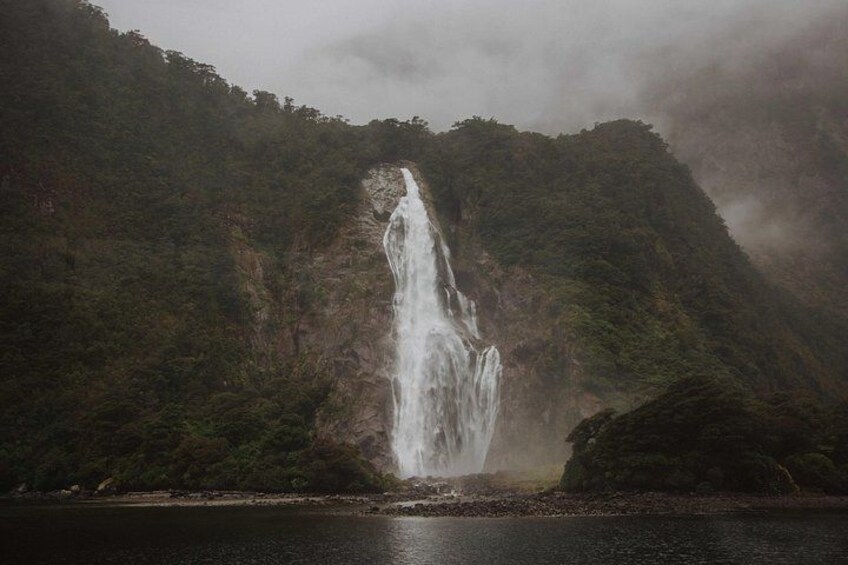 A waterfall cascading down a steep cliff surrounded by dense forest. 3