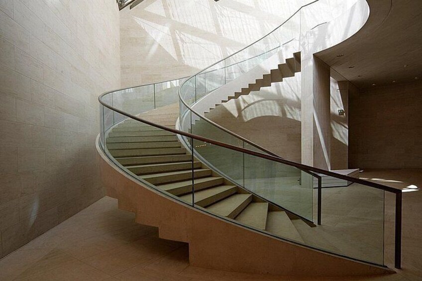 A spiral staircase with glass railings inside a building. 4