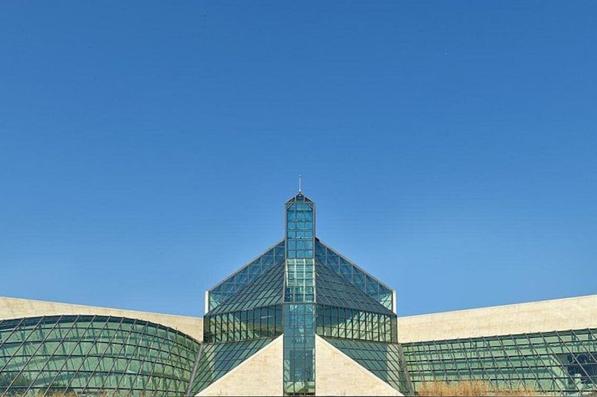 A modern building with a glass facade and a unique geometric design. 1
