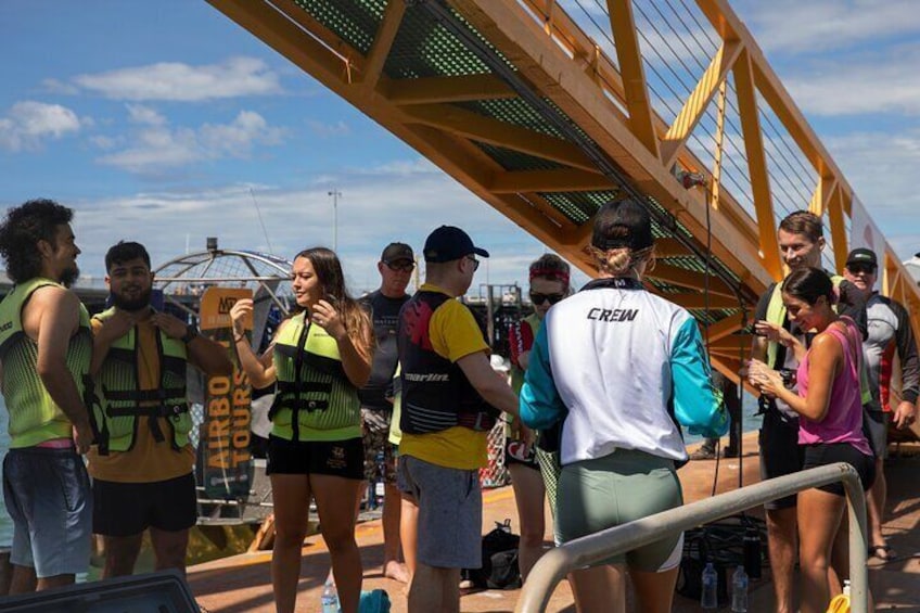 A group of people standing on a bridge, some wearing vests labeled "CREW". 4