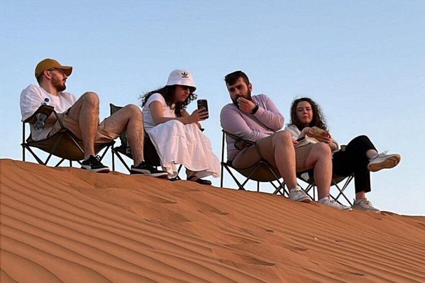 Four people sitting on a dune in a desert landscape. 2
