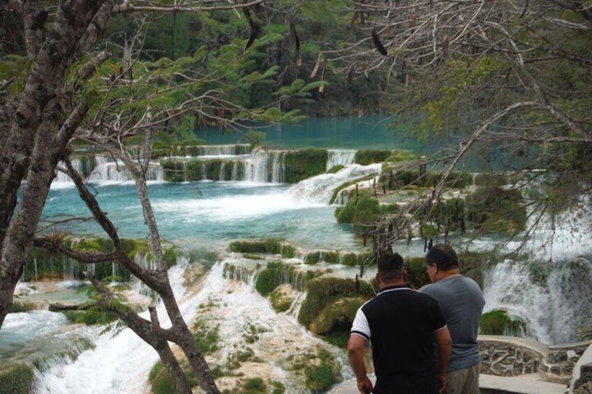 A waterfall cascading over terraced pools surrounded by trees. 4