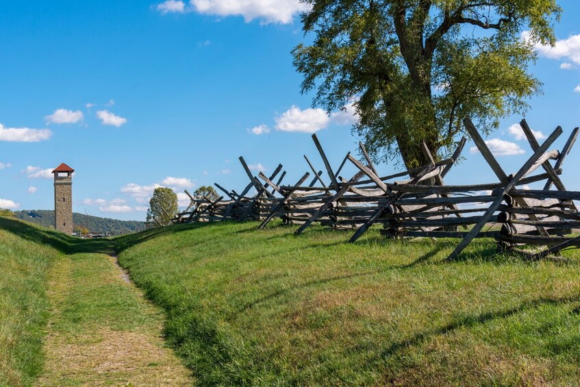 Un sentier herbeux menant à une tour de pierre et à une clôture en bois. 1
