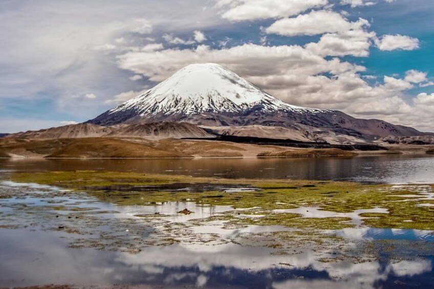 A snow-capped mountain, a reflective lake, and a cloudy sky. 1