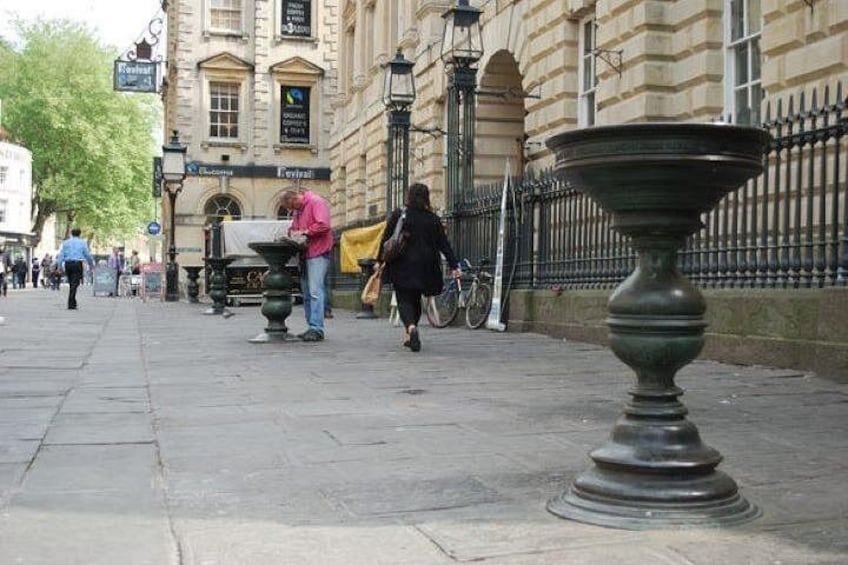 A city street with pedestrians, a bicycle, and classical architecture. 5