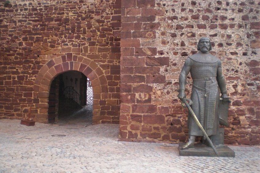 Une arche en pierre et une statue d’une figure historique tenant une épée et un bouclier. 3