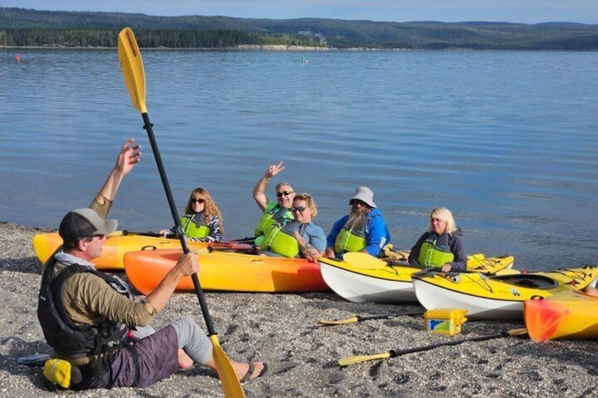 People in kayaks on a sandy shore by a lake. 5