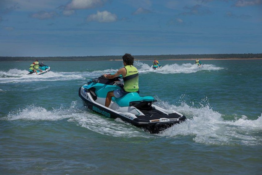 Eine Person fährt einen Jetski auf dem Wasser, im Hintergrund sind weitere Jetskis zu sehen. 2
