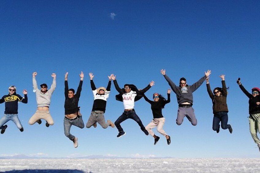 A group of people jumping in the air against a clear sky. 4
