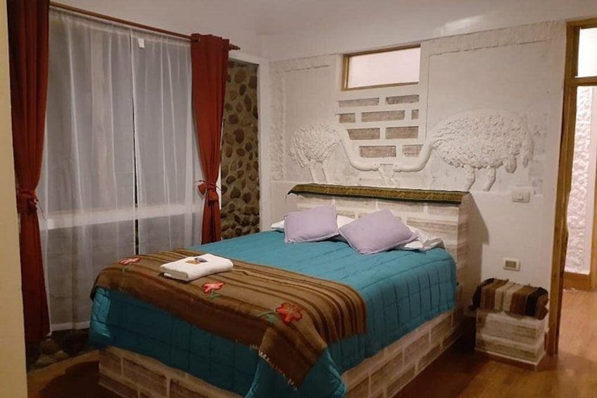 A bedroom with a bed, curtains, a window, and a wall with a sheep carving. 3