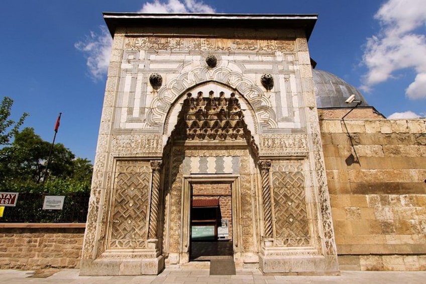 An ornate stone archway with intricate carvings and a dome structure in the background. 2
