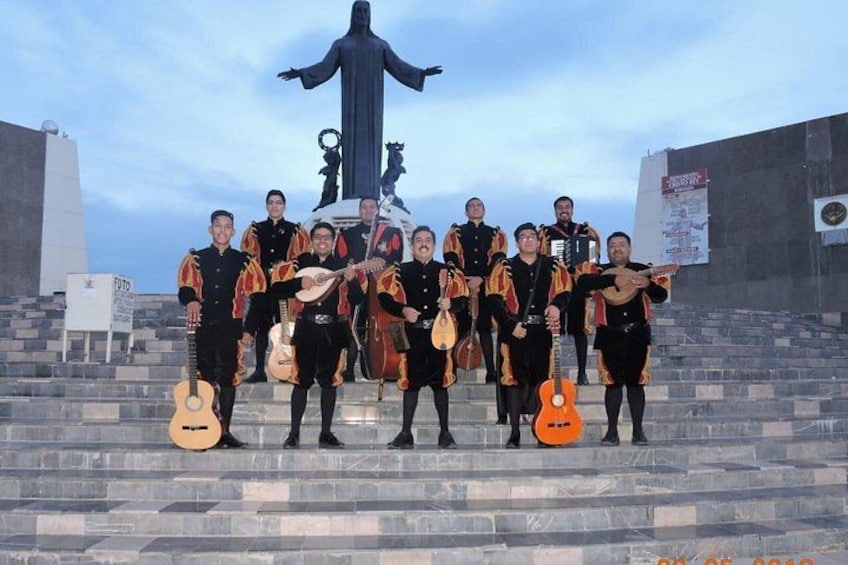 Een groep muzikanten treedt op trappen op, met een standbeeld op de achtergrond. 3