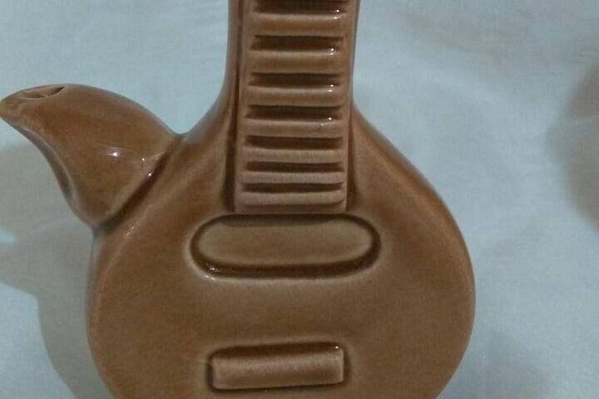 Een keramieken gitaar met een bruine afwerking en een slagplaat. 2