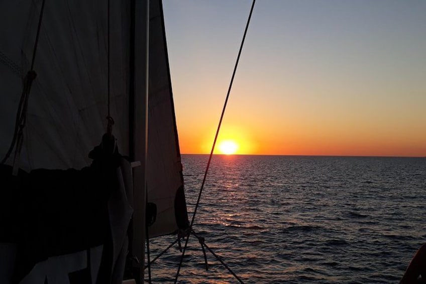 A sunset over the ocean with a sailboat. 2
