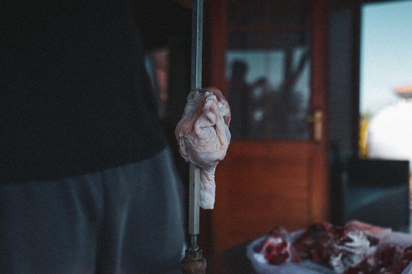 A person holding a meat skewer with a piece of meat on it. 2