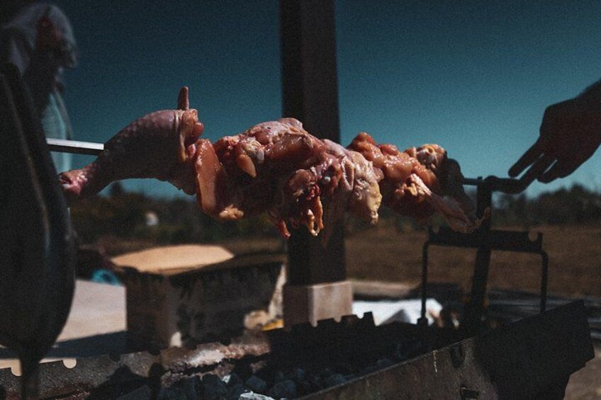 A person grilling meat on a spit over an open flame. 3
