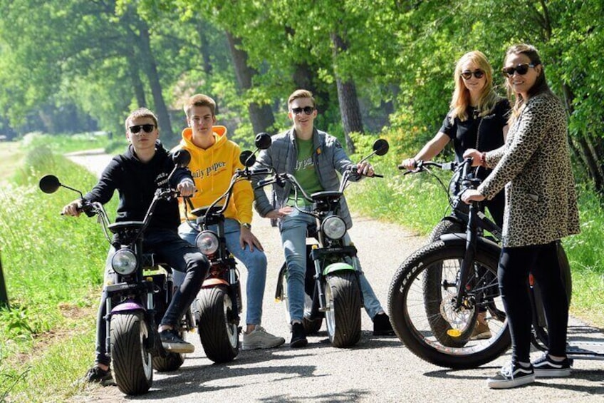 A group of people on electric bikes on a paved path surrounded by greenery. 5