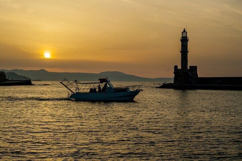 Un bote sobre aguas tranquilas, con un faro al fondo durante el atardecer. 1