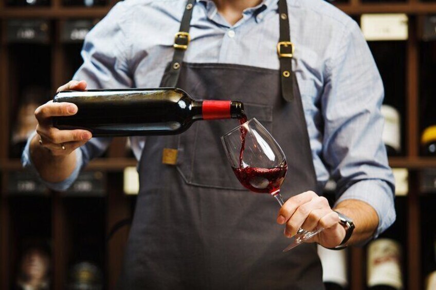 Una persona sirve vino tinto de una botella a una copa. 4